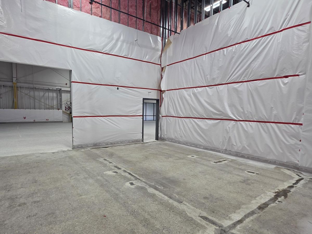 Temporary containment partitions separating active construction from an operating facility